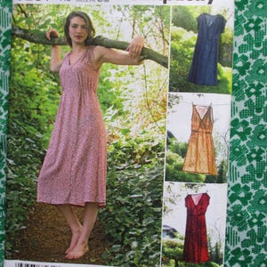 Puede incluir: Un patrón de costura vintage con una mujer con un vestido floral rosa. El patrón incluye imágenes de vestidos en azul, naranja y rojo. El fondo es una tela verde con estampado floral.