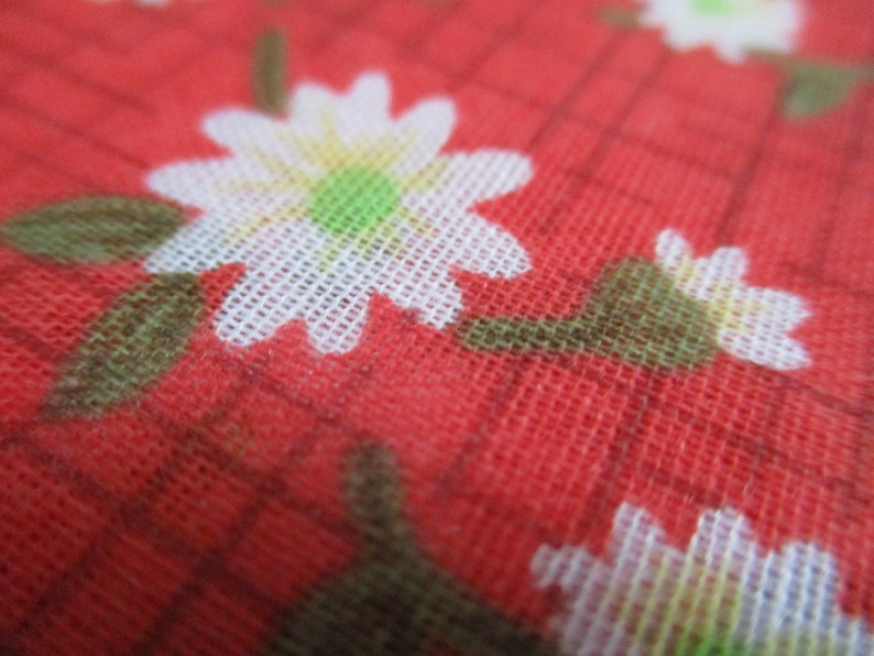 K&ouml;nnte beinhalten: Roter Stoff mit einem wei&szlig;en Blumenmuster. Die Blumen sind klein und haben ein schlichtes Design. Der Stoff hat eine gewebte Textur.