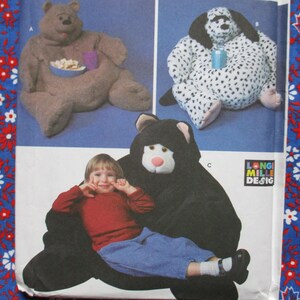 May include: Image of a sewing pattern featuring three plush animal designs: a brown bear, a Dalmatian, and a black bear. The brown bear holds a bowl and cup. The black bear is shown with a child. The Long Mille Design logo is visible.