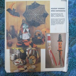 May include: A vintage craft pattern for Halloween decorations. The pattern includes instructions for making a witch doll, a spiderweb wall hanging, a pumpkin windsock, and a Santa windsock. The pattern is printed on a white background with a blue floral pattern on the side.