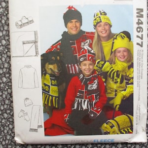 May include: A sewing pattern envelope featuring a family wearing matching red, black, and yellow fleece hats, scarves, and jackets. The pattern includes illustrations of a blanket, turtleneck, hat, mittens, and scarf. The text "FABULOUS FLEECE" is visible.