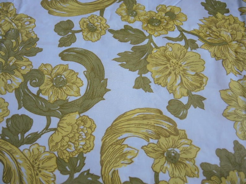May include: A white fabric with a repeating pattern of yellow flowers and stylized leaves. The flowers are in various sizes and shapes, with some having a more detailed design than others.