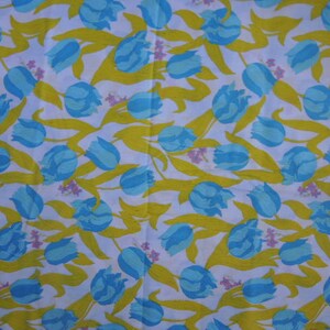 May include: White fabric with a repeating pattern of blue and yellow tulips. The tulips are stylized and have a simple design.