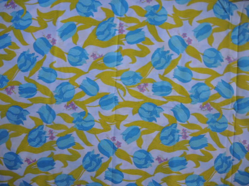 May include: White fabric with a repeating pattern of blue and yellow tulips. The tulips are stylized and have a simple design.