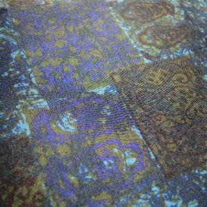 May include: A close-up of a fabric with a blue, green, and brown paisley pattern. The fabric has a soft, textured surface.
