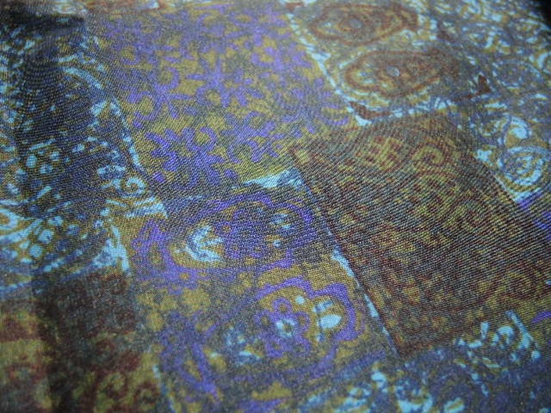 May include: A close-up of a fabric with a blue, green, and brown paisley pattern. The fabric has a soft, textured surface.