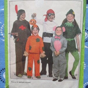 May include: A vintage sewing pattern featuring children in Halloween costumes. Costumes include a Native American, a pumpkin, a pirate, a mouse, and Peter Pan. The pattern includes instructions for appliqués.