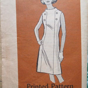 May include: Vintage sewing pattern featuring a line drawing of a sleeveless dress with a high collar and button details. The illustration is in black and white on a brown background, with the words "Printed Pattern" at the bottom.