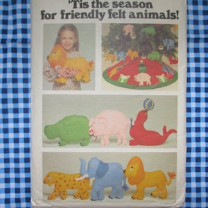 May include: A vintage sewing pattern featuring felt animal ornaments for a Christmas tree. The pattern includes a variety of animals, including a lion, elephant, pig, seal, turtle, and leopard. The pattern also includes a felt tree skirt with a Christmas tree design.