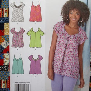 May include: A woman wearing a floral print top and lavender pants. The image also shows a sewing pattern with various top designs. The background features a colorful patchwork fabric.