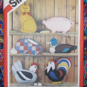 May include: A vintage sewing pattern for making five plush animal toys. The pattern includes a cat, pig, rabbit, duck, and rooster. The animals are all brightly colored and have a patchwork design.