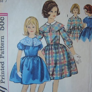 May include: A vintage sewing pattern for a girl's dress. The pattern is for a dress with a Peter Pan collar and a plaid skirt. The pattern number is 500C.