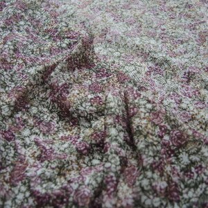 May include: A close-up of a fabric with a floral pattern. The fabric is a mix of white, pink, and green colors. The pattern is small and delicate.