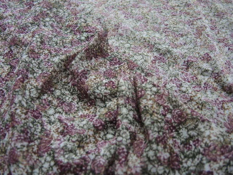 May include: A close-up of a fabric with a floral pattern. The fabric is a mix of white, pink, and green colors. The pattern is small and delicate.