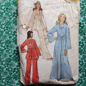 May include: Vintage sewing pattern featuring illustrations of women's clothing designs. The designs include a long blue dress, a white tunic and pants, and a red outfit with flared pants. The pattern is on a worn, cream-colored paper.