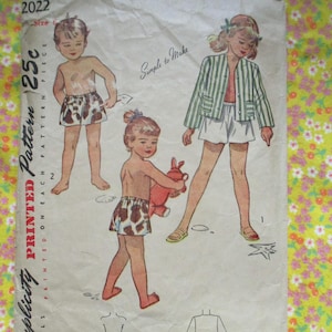 May include: Vintage sewing pattern for children's clothing. The pattern is for a pair of shorts and a jacket. The pattern is printed on a white background with a floral pattern. The pattern is from Simplicity and is dated 2022. The pattern is for size 2 and costs 25 cents.