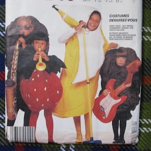 May include: A sewing pattern featuring children in fruit and musical instrument costumes. The costumes include a banana, strawberry, and a guitar. The text on the pattern reads "COSTUMES DEGUISEZ-VOUS" and "FUNKY FRUIT".