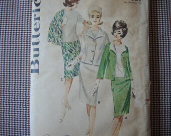 Può includere: Un modello di cucito vintage con tre disegni di abiti per donne. Gli abiti sono in diversi stili e colori, tra cui un abito verde con colletto bianco, un abito bianco con colletto verde e un abito a fantasia verde e bianco. Il modello è di Butterick ed è etichettato "The Countess 7012".