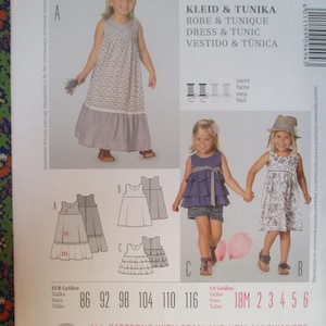 Puede incluir: Un patrón de costura para un vestido y una túnica con instrucciones en inglés, alemán, francés, español e italiano. El patrón incluye tallas para niños de 18 meses a 6 años. El patrón está ilustrado con fotos de niños usando las prendas terminadas.