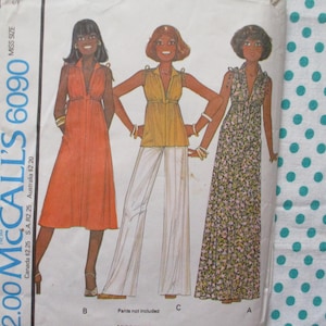 May include: Vintage McCall's 6090 sewing pattern showing three dress and top designs. The pattern includes a long orange dress, a yellow top with white trousers, and a floral print dress. The pattern is for Miss sizes.