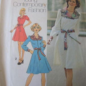 May include: A sewing pattern featuring two dresses. The dress on the left is a red dress with a white collar and a white belt. The dress on the right is a white dress with a colorful patterned sash and a colorful patterned collar. The text "Young Contemporary Fashion" is printed at the top of the pattern.