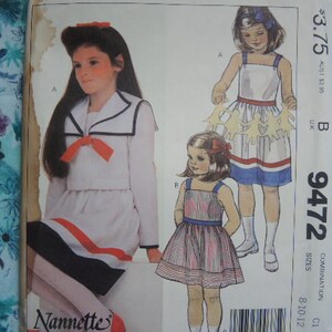 Puede incluir: Un patrón de costura para dos vestidos de niños. El patrón es para las tallas 8-10-12. El primer vestido es un vestido blanco con un ribete rojo y azul y un cuello marinero. El segundo vestido es un vestido a rayas rojas y blancas con un corpiño blanco. El patrón se llama "Tallas combinadas 8-10-12" y el número es 9472.