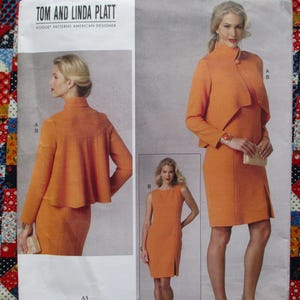 May include: Vogue Patterns American Designer Tom and Linda Platt. The image shows a woman in an orange dress and matching jacket. The dress is knee-length with a slit, and the jacket has a draped design. A smaller image shows a sleeveless dress.