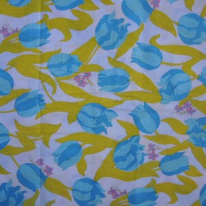 May include: White fabric with a repeating pattern of blue and yellow tulips. The tulips are stylized and have a simple design.