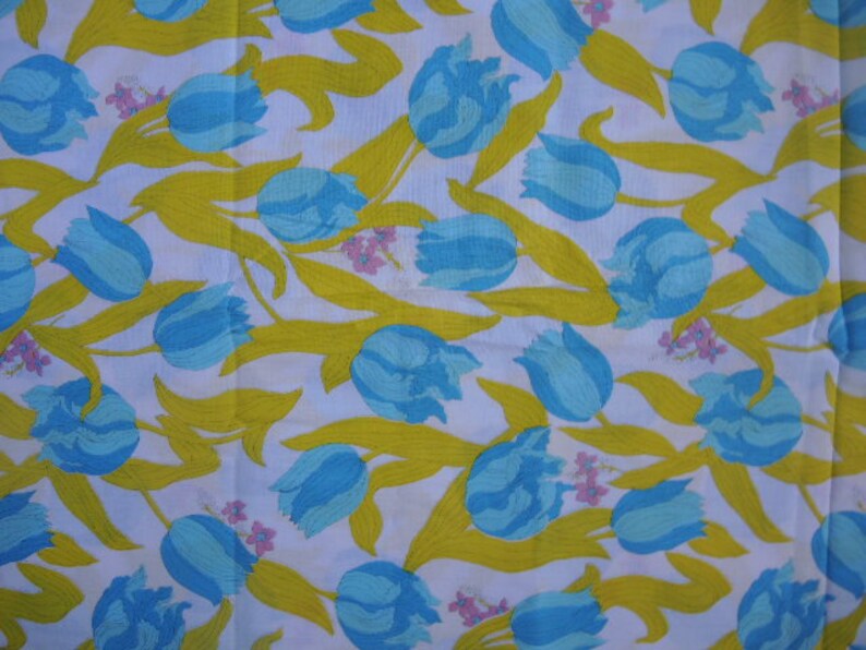 May include: White fabric with a repeating pattern of blue and yellow tulips. The tulips are stylized and have a simple design.