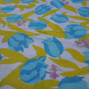 May include: White fabric with a repeating pattern of blue and yellow tulips. The tulips are stylized and have a retro look.