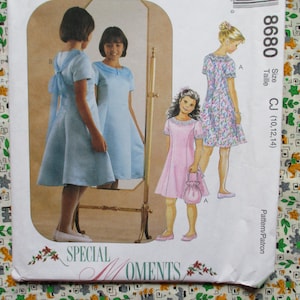 May include: A vintage sewing pattern featuring illustrations of girls in dresses. The pattern includes a light blue dress with a bow, a pink dress, and a floral print dress. The pattern is labeled "Special Moments" and includes size information.