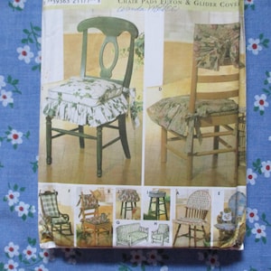 May include: A vintage sewing pattern for chair pads and glider covers. The pattern features illustrations of chairs with floral-patterned cushions and covers. The main image shows two chairs, one with a green frame and the other with a wooden frame.