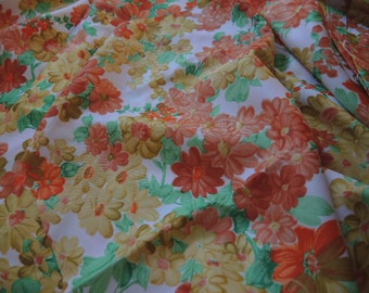 May include: White fabric with a floral pattern featuring orange, yellow, and green flowers. The fabric is wrinkled and has a sheer texture.