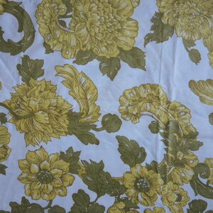 May include: A white fabric with a floral pattern featuring yellow flowers with brown centers and green leaves. The flowers are arranged in a repeating pattern.