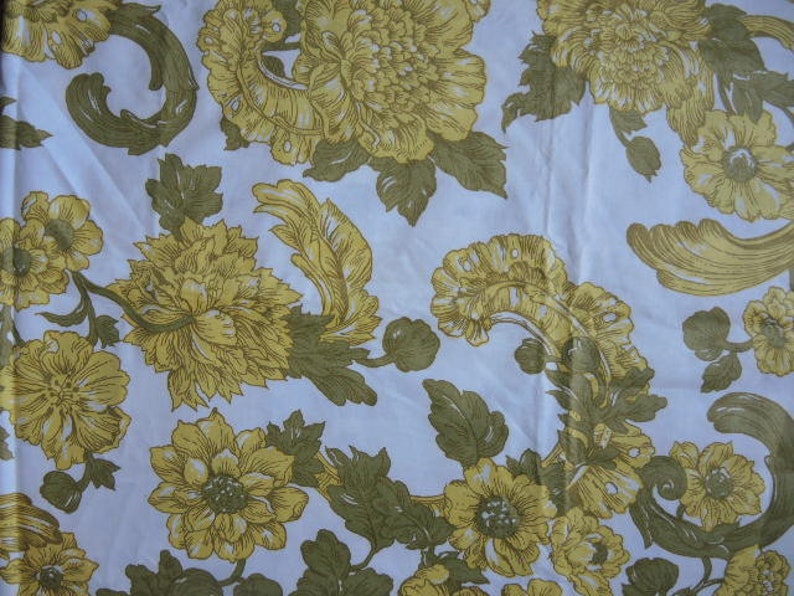 May include: A white fabric with a floral pattern featuring yellow flowers with brown centers and green leaves. The flowers are arranged in a repeating pattern.