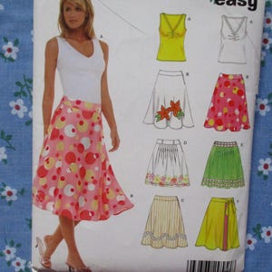 May include: A sewing pattern featuring a woman wearing a white top and a pink skirt with large, colorful polka dots. The pattern includes illustrations of various skirt and top designs, with a blue floral fabric in the background.