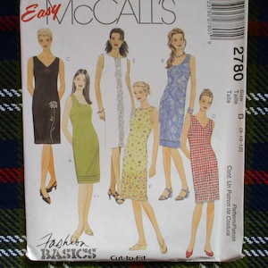May include: A sewing pattern package featuring illustrations of various dresses. The package includes the text "Easy McCall's" and "Fashion Basics". The dresses are in different styles and colors, including a black dress, a green dress, and a red and white checkered dress.