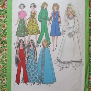 May include: A vintage sewing pattern featuring ten different doll outfits. The outfits include a long white wedding dress, a green pantsuit, a blue jumpsuit, a red pantsuit, a yellow dress, a blue cape, and several other dresses. The pattern is printed on white paper with black text and illustrations.