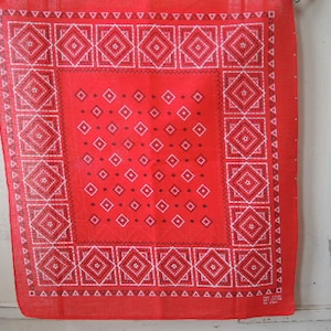 May include: Red bandana with a white diamond pattern. The bandana has a white border with a repeating triangle design.