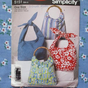 May include: Simplicity pattern 5151 featuring various fabric handbags. The bags include a blue quilted bag, a striped bag with a bamboo handle, a red floral bag, and a small bag with a blue and green pattern. The pattern is labeled "One Size".