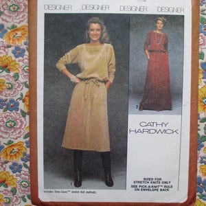 Può includere: Un cartamodello per due abiti, uno marrone e uno bordeaux. Il cartamodello è di Cathy Hardwick ed è adatto per maglie elasticizzate. Il cartamodello include istruzioni per i metodi di maglia elasticizzata Time-Saver.