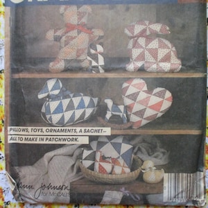 Puede incluir: Un patrón de costura vintage con instrucciones para hacer almohadas, juguetes, adornos y una bolsita de patchwork. El patrón incluye una variedad de diseños, incluyendo un oso, un conejito, un pato y un corazón. El patrón es de Ann Johnson para McCall's.