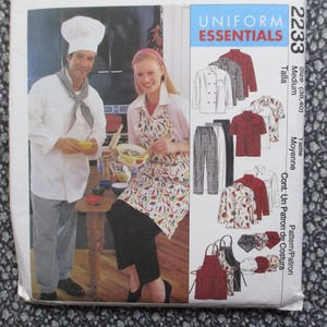 May include: A sewing pattern for Uniform Essentials, featuring a chef and a woman in an apron. The pattern includes designs for chef coats, shirts, pants, aprons, and chef hats. The size is medium.