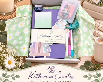 May include: A stationery gift box lined with daisy-patterned tissue paper containing a purple notebook with a Katherine Creates belly band, a stack of light green sticky notes, a roll of floral washi tape, a bookmark, and a set of colorful pens.