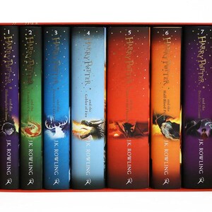 Könnte beinhalten: Ein siebenbändiges Harry Potter Buchset von J.K. Rowling in einer roten Box. Die Buchrücken zeigen verschiedene Farben wie Violett, Grün, Blau, Hellblau, Rot, Orange und Dunkelviolett, jeweils mit dem Titel und einer einzigartigen Illustration.