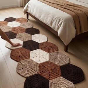 Puede incluir: Una alfombra de pasillo larga y estrecha compuesta por hexágonos de ganchillo interconectados en una paleta de crema, beige, marrón claro y marrón oscuro. La alfombra presenta un patrón geométrico y está sobre un suelo de madera claro.