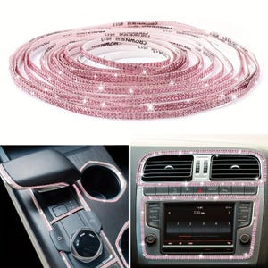 Op de afbeelding: Een rol roze strass-plakband met een herhalende Crown #513-opdruk op de achterkant. De strip is aangebracht als decoratieve rand rondom de versnellingspook, bekerhouders en het infotainmentscherm van de middenconsole in een auto.