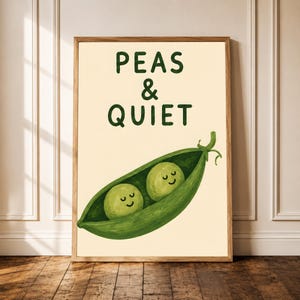 May include: A framed wall art print on a light cream background featuring a green pea pod with two smiling peas inside. The text above the pea pod is written in dark green capital letters and reads PEAS & QUIET in a simple sans-serif font.