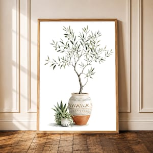 Könnte beinhalten: Ein gerahmter Wandkunstdruck mit einer Aquarellillustration eines Olivenbaums in einem gemusterten Terrakottatopf, begleitet von einer kleineren Topfsukkulente mit herabhängendem grünem Laub vor einem weißen Hintergrund.