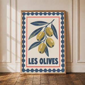 May include: A rectangular wall art print featuring a stylised illustration of a branch with three green olives and dark blue leaves. The design is enclosed in a dark blue scalloped border and a thin red frame, with the text LES OLIVES in blue.